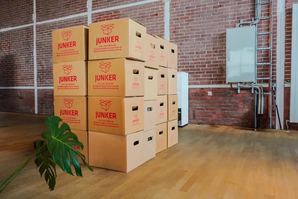 Gestapelte Umzugskartons der Umzugsfirma Junker Berlin in leerem Raum