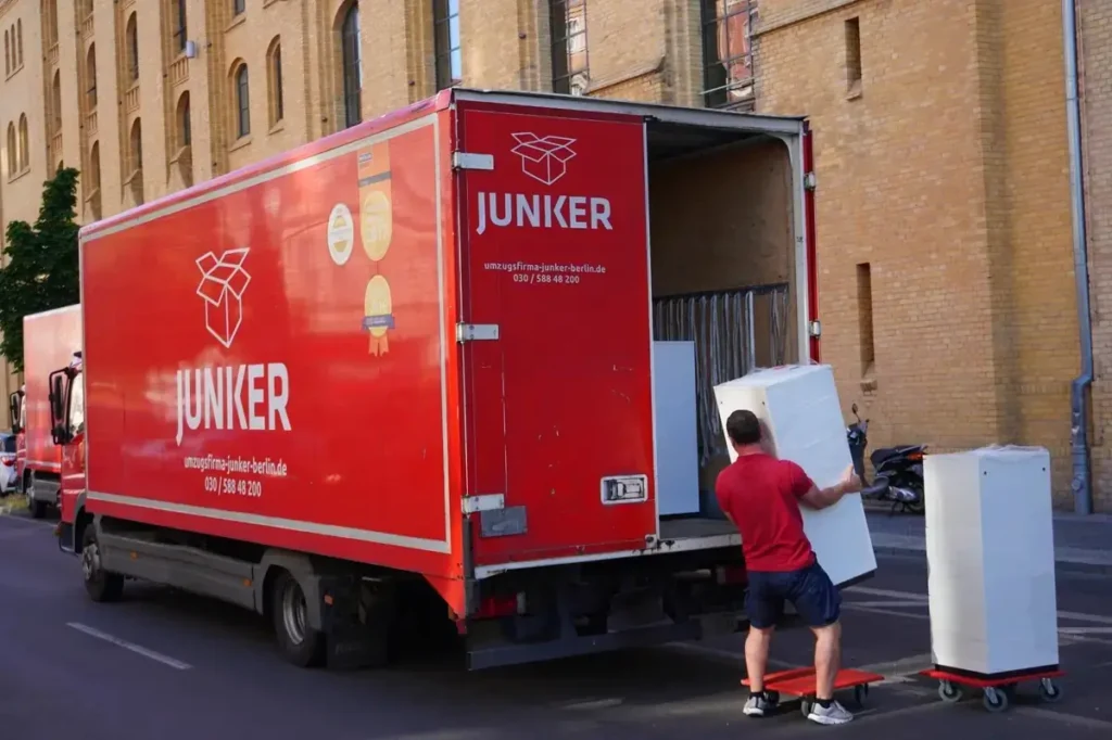 Mitarbeiter der Junker Umzugsfirma GmbH beim Beladen eines roten Umzugs-Lkw in Berlin