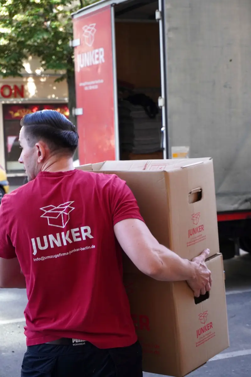 Umzugshelfer der Junker Umzugsfirma trägt Umzugskartons in Berlin