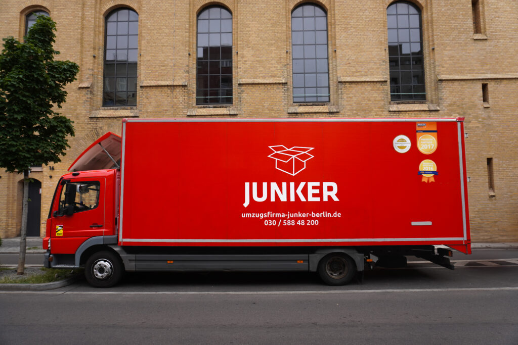 Roter Umzugswagen der Junker Umzugsfirma steht vor einem Gebäude in Berlin.